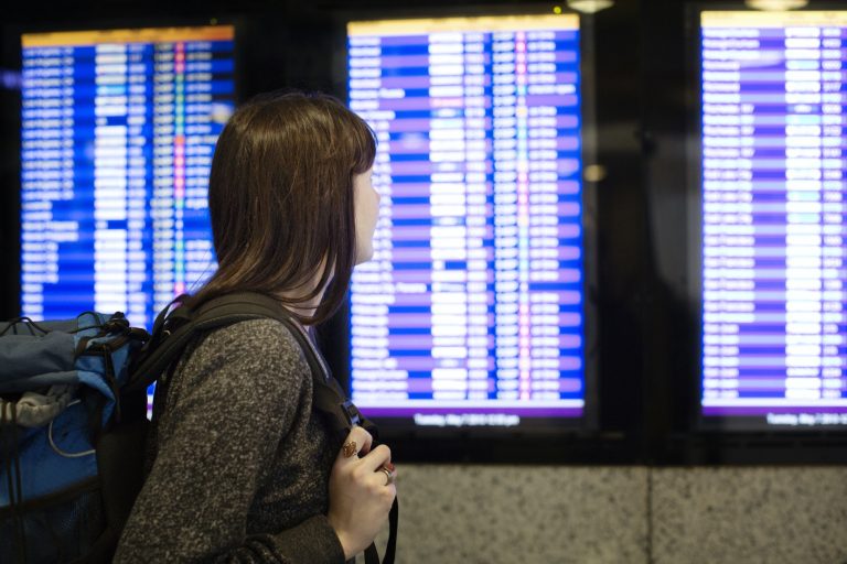 Side View Of Woman Looking At Arrival Departure Board